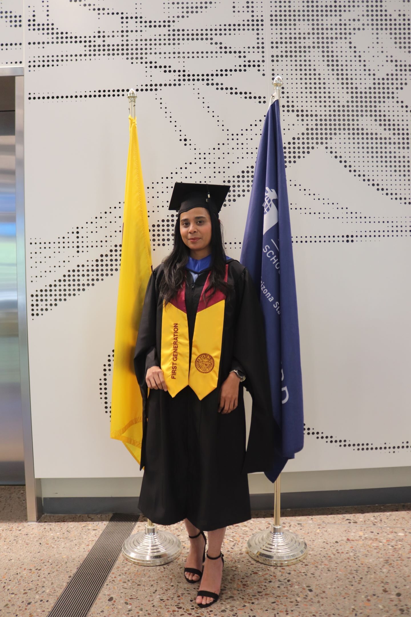 Nina a graduating student poses in front of flags